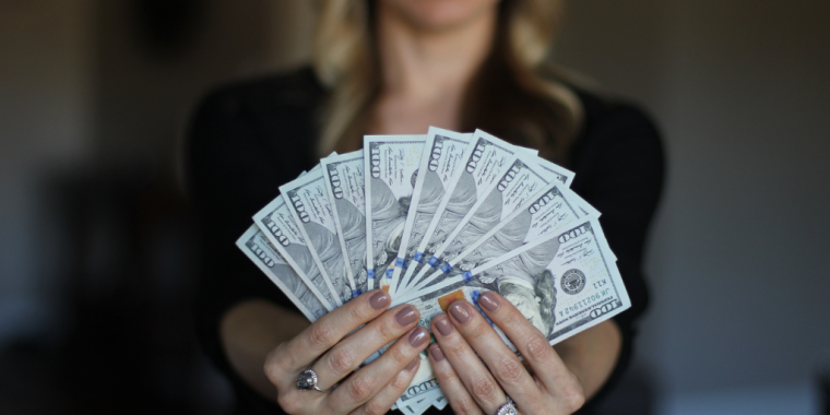 Woman holding a fan of American one-hundred dollar bills