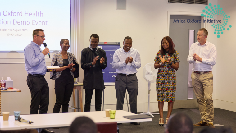 A group of African speakers, two male and two female, standing in front of an audience.